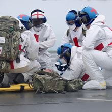 crewmembers dressed in emergency white clothing and blue helmets on deck of aircraft carrier