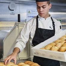 white uniformed chef arranging bread rolls onto trays