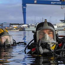 Divers in full gear in the water look at the camera
