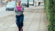 woman running on on footpath next to a road