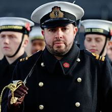 Royal Navy officer stands with a sword on his shoulder