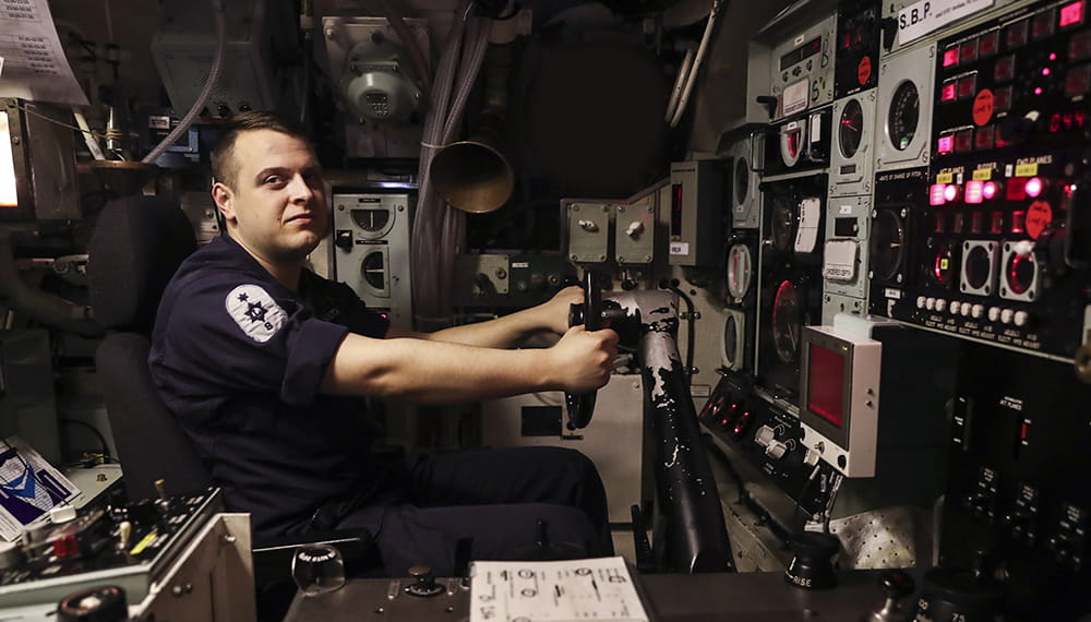royal navy submariner maintaining the watch working on equipment on board boat