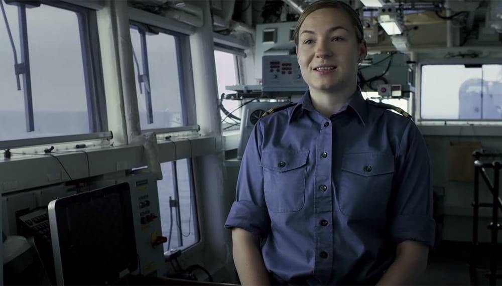 Navy personnel smiling at camera whilst taking part in an interview on a boat.