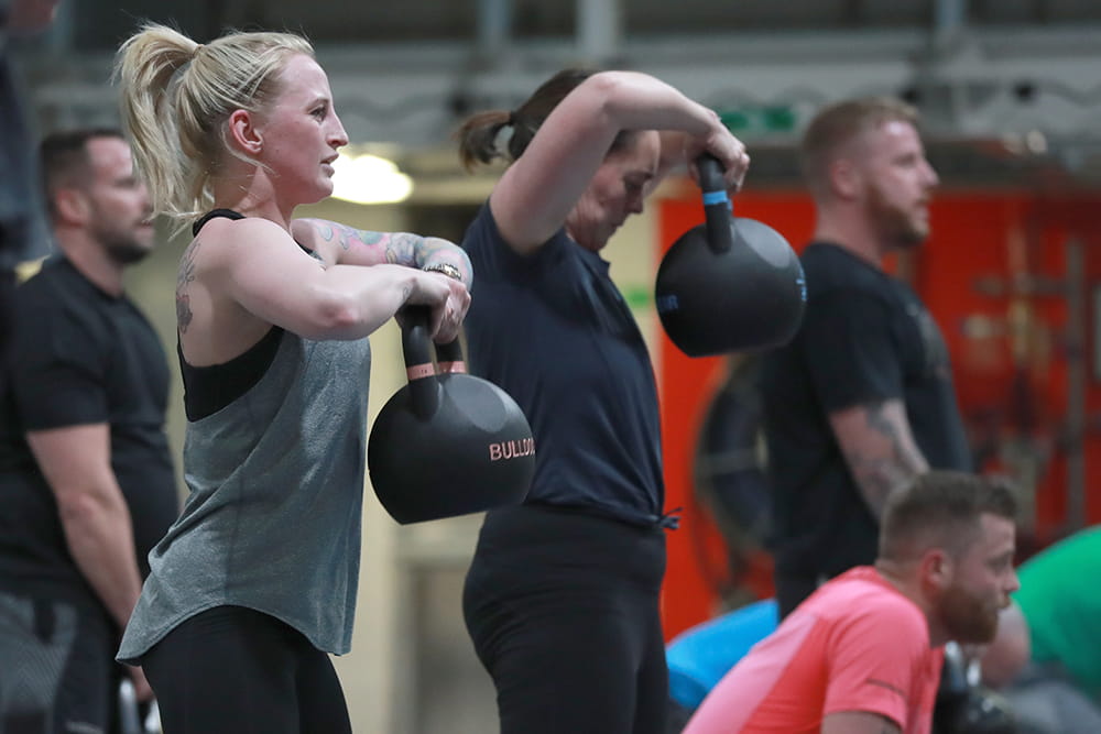 royal navy personnel in gym wear completing exercises with kettle bells