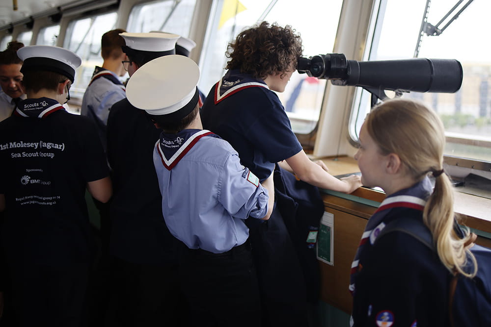 group of sea cadets on bridge of ship with one cadet looking through binoculars