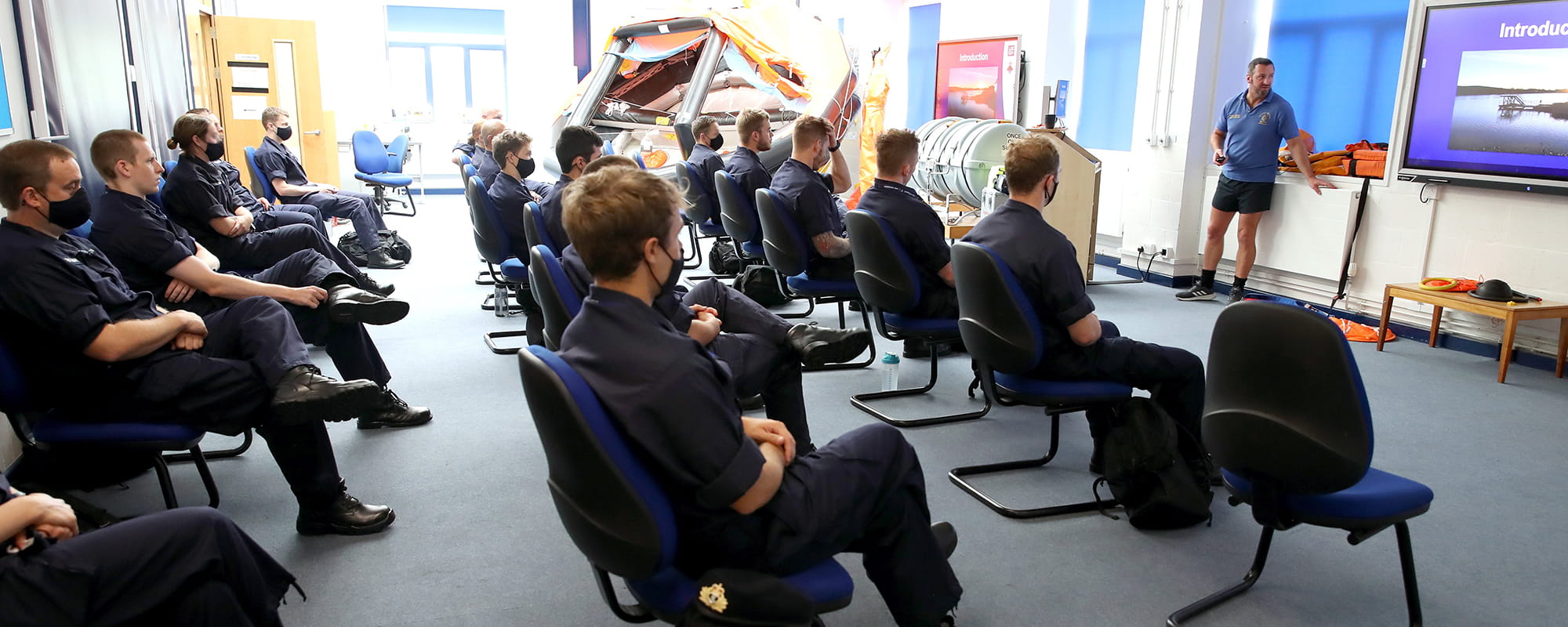 Royal Navy Reserve Officer Cadets sitting in a classroom watching the instructor