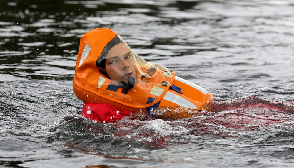 Royal Navy Reserve Officer Cadet training in water at Britannia Royal Naval College wearing an orange inflatable
