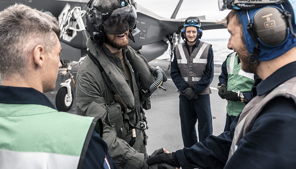 Personnel shake hands and smile. HMS Queen Elizabeth has embarked, for the first time UK F-35B Lightning II fighter jets during ‘WESTLANT 19’.