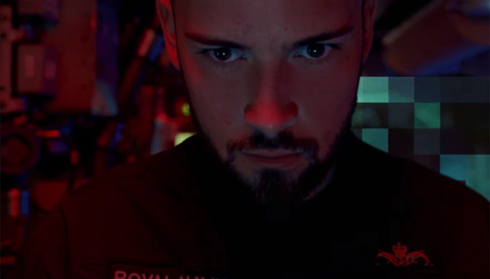 The image shows a close up of navy personnel face which is lit by red lighting. Navy technology is advanced. It is used to identify, track and destroy potential threats. 