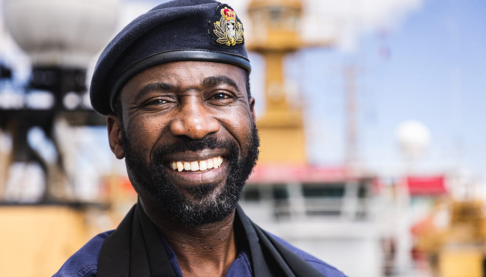 close up image of a beaming royal navy pastor in blue uniform and beret