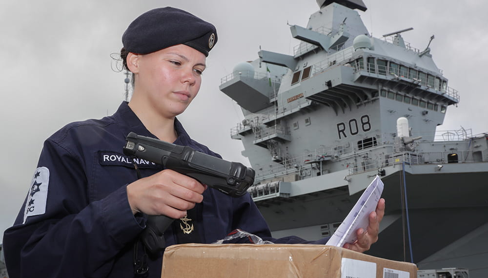 blue uniformed royal navy logistics crewmember scanning incoming stores using Hand Held Device