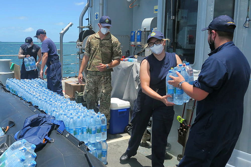 Royal Navy sailors unload large amounts of water bottles as a part of disaster relief