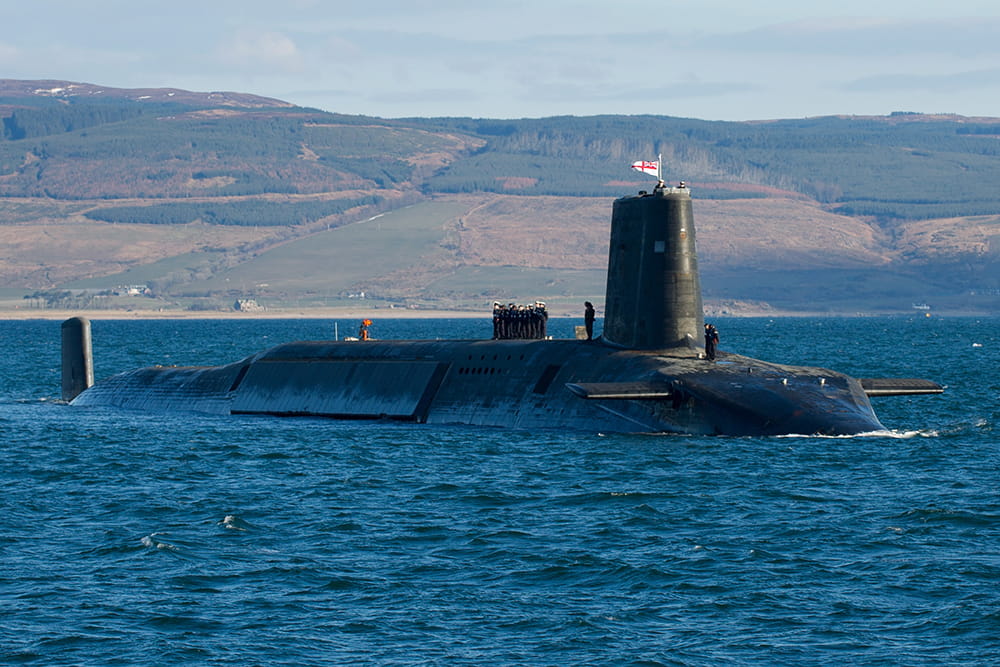 Vanguard Class submarine on the surface in front of Scottish countryside