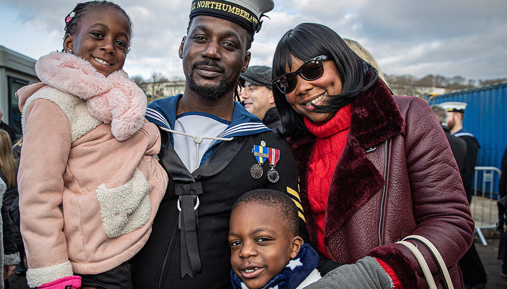 HMS Northumberland sailor with wife and two children smiling at camera