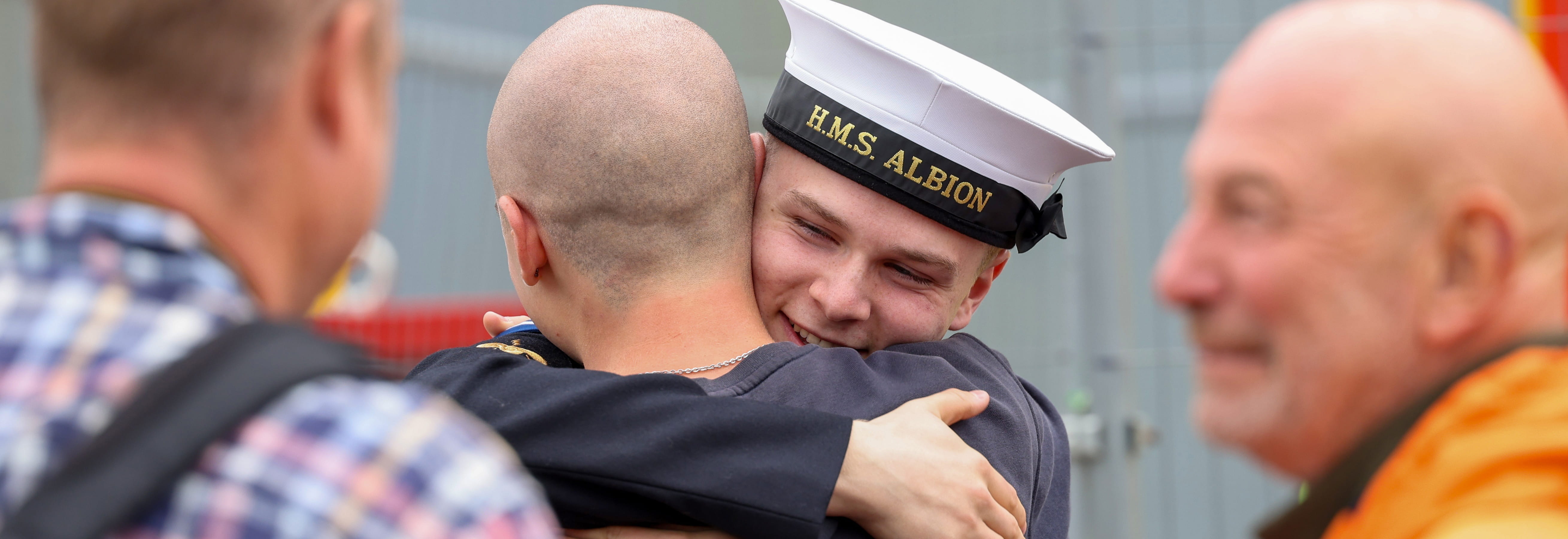 A member of HMS Albion's ships company embracing a family member.