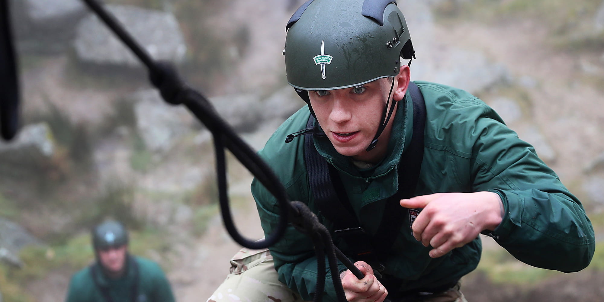 Royal Marine carrying out climbing training wearing green helmet