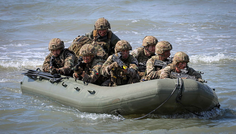 Several Royal Marine commandos with guns in a small green inflatable raiding craft 