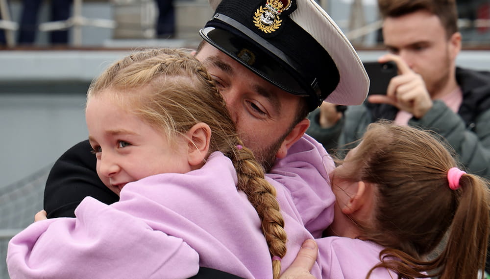 Royal Navy Lieutenant hugs his two daughters