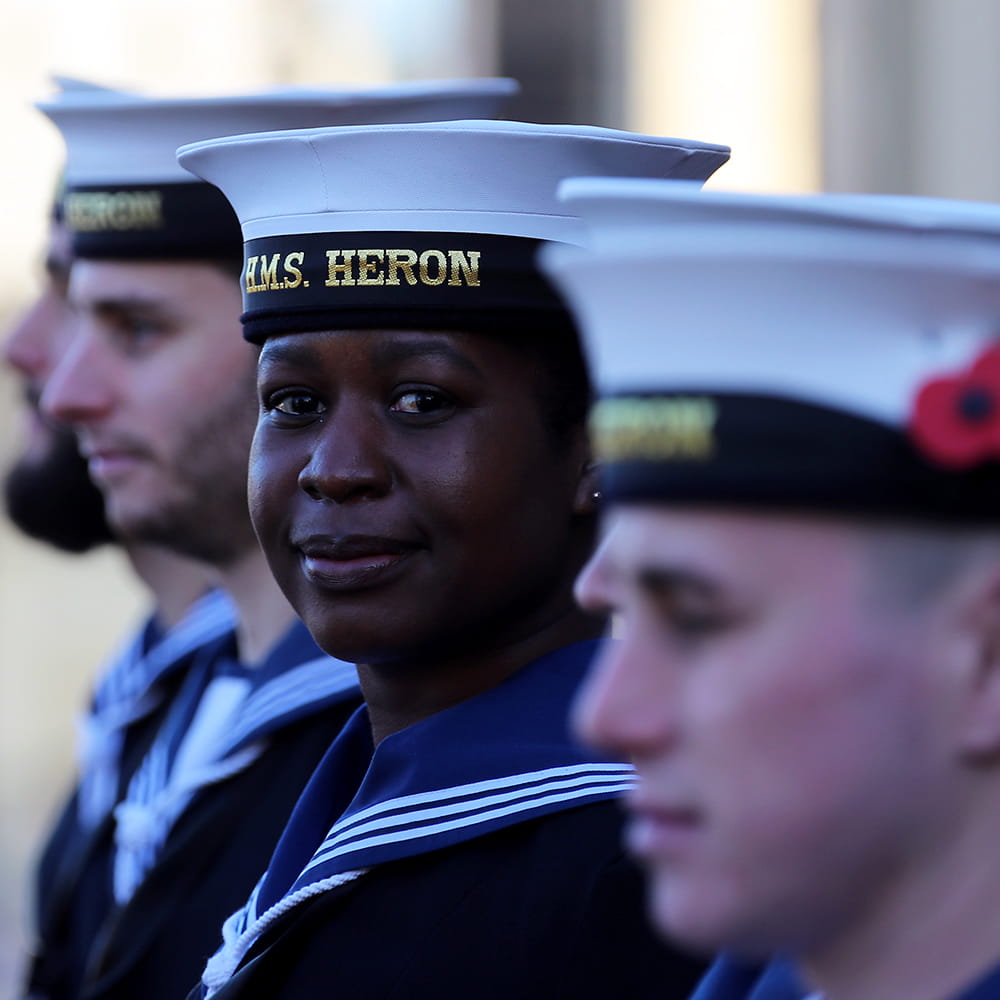 Royal Navy sailors on parade, one lady smiles at the camera