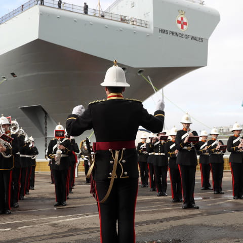 Royal Marines band play in front of the HMS Prince of Wales aircraft carrier